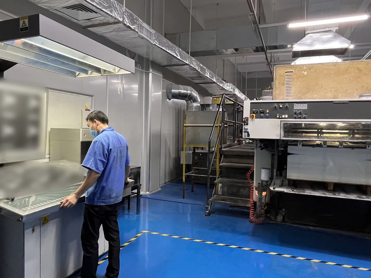 Operator checking printed sheets at the colour viewing table beside an offset printing press in the FuRui Pack factory